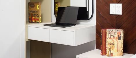 Un dormitorio con escritorio blanco, computadora portátil, espejo y cama.