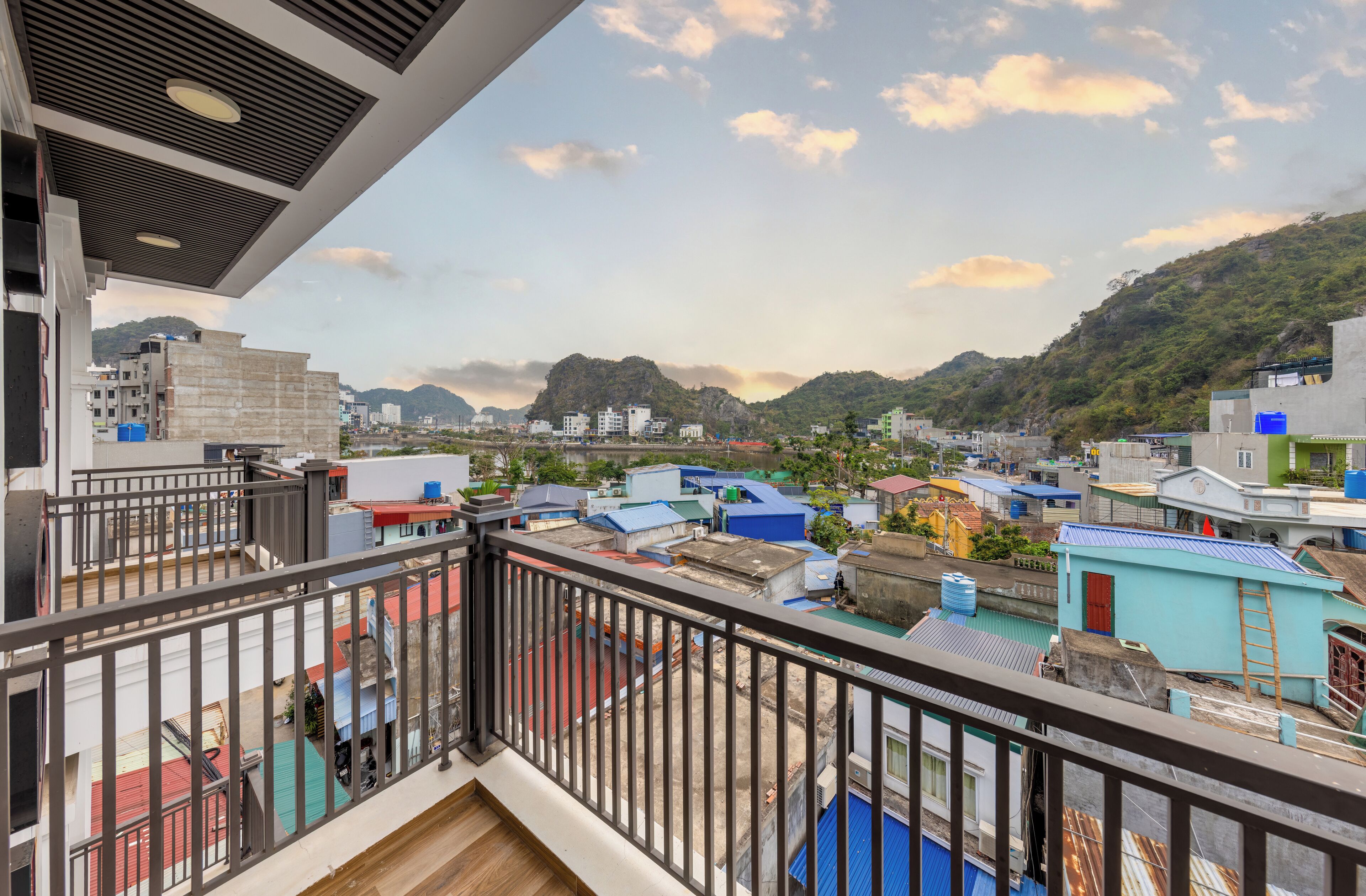 A balcony with a view of a residential area, including buildings and a hill in the background.