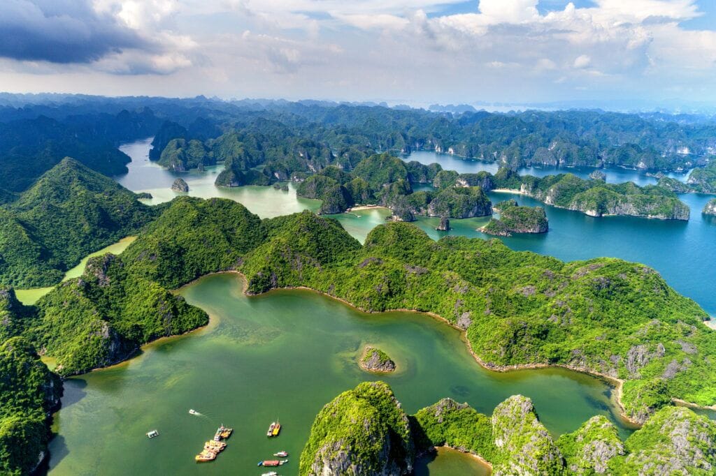 Une vue aérienne d’un paysage verdoyant et luxuriant, parsemé de nombreuses petites îles et bordé d’eaux cristallines.