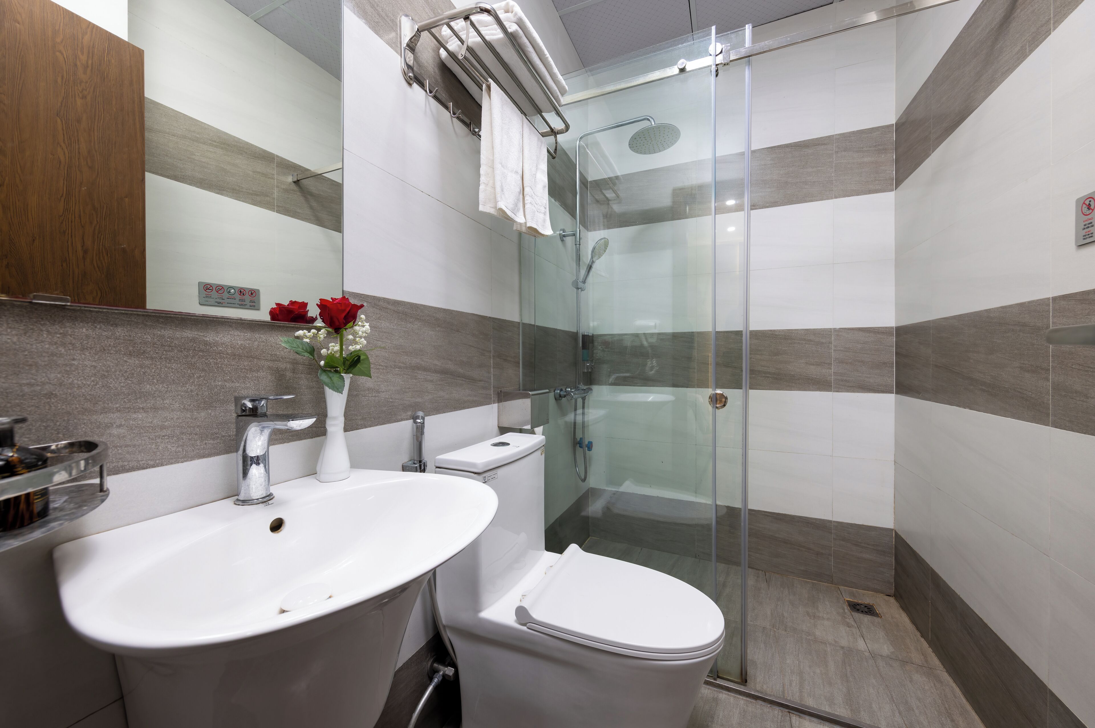 Un baño moderno con ducha acristalada, lavamanos blanco y retrete.