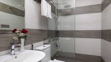Un baño moderno con ducha de vidrio, un lavabo blanco y un inodoro.