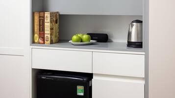 A kitchen with a flat-screen TV mounted above a countertop, a dishwasher below, and a kettle on the counter.