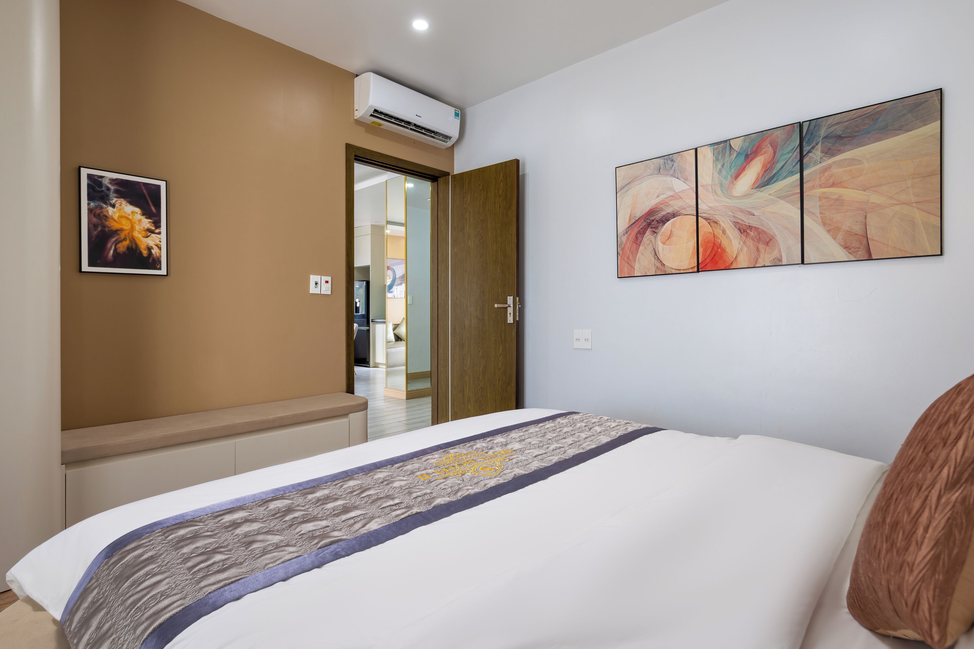 Habitación de hotel con cama, puerta de madera, aire acondicionado montado en la pared y un cuadro.