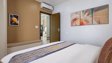 Habitación de hotel con cama, puerta de madera, aire acondicionado montado en la pared y un cuadro.