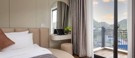 Une chambre d’hôtel avec un lit, un bureau avec un ordinateur portable, un miroir et une vue sur l’extérieur.