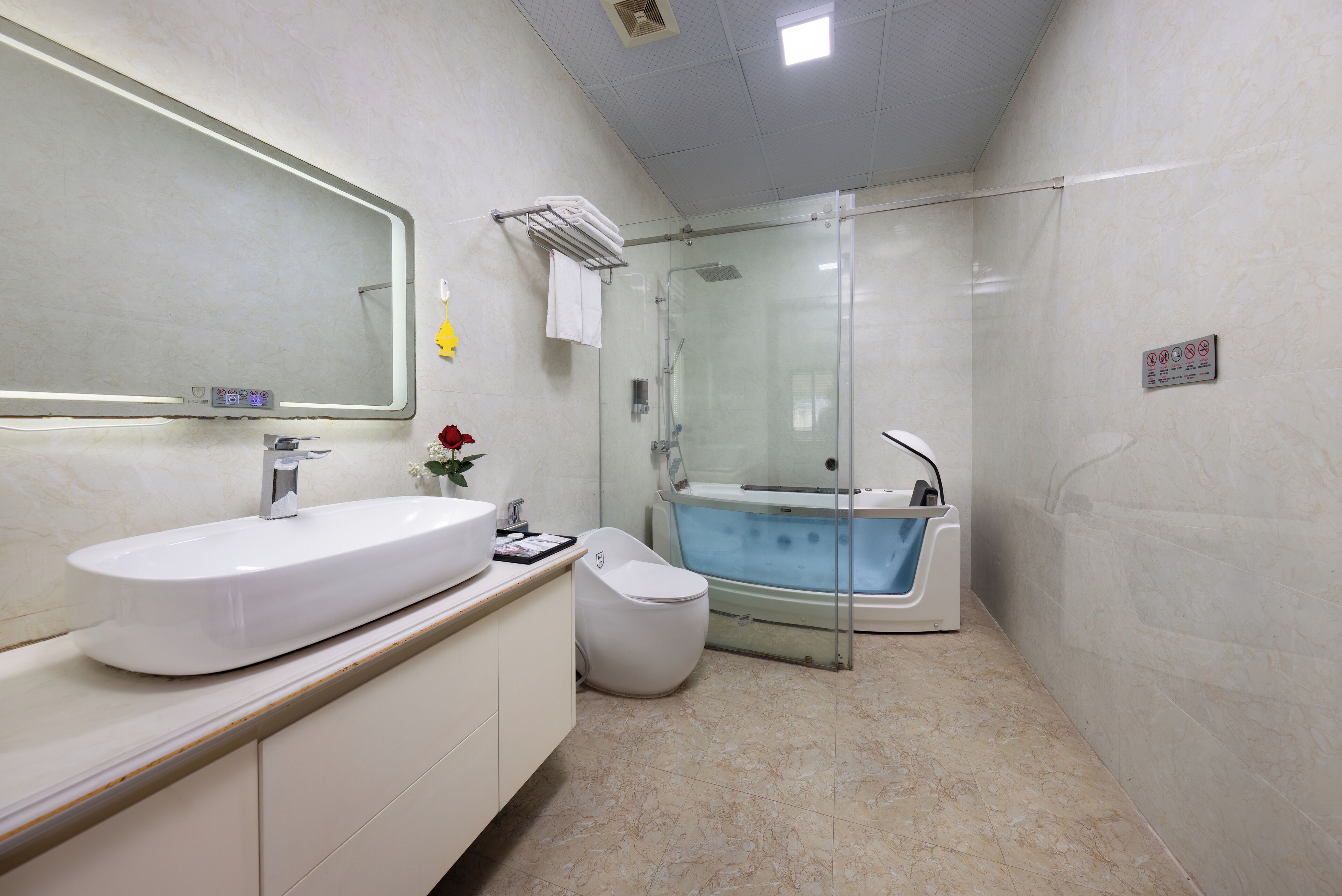 A modern bathroom with a large mirror, a white sink, a toilet, and a glass-enclosed shower area.