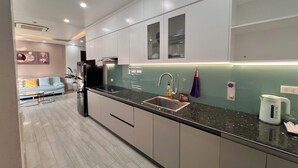 A modern kitchen with white cabinets, a black countertop, and a stainless steel sink. - Cat Ba Seoul 2 Hotel & Apartment (Hai Phong)
