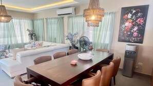 A dining area with a wooden table, six chairs, and a fan. There is a sofa and a painting on the wall. - Sky I Village Bavaro (Punta Cana)