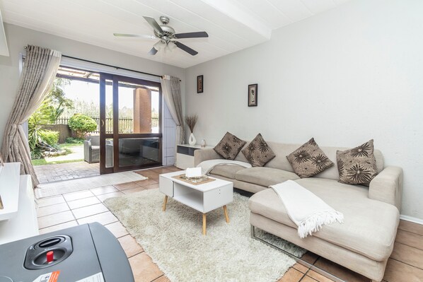 A living room with a sofa, coffee table, and a ceiling fan.