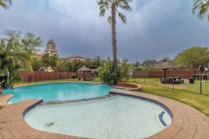 Una piscina con borde de azulejos, rodeada por un patio de ladrillo.