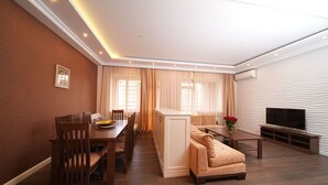 A modern living room with a dining area, a sofa, a TV, and a kitchen island. - Mount Ararat View 2-bedroom Luxury Apartment by Sweet Home (Yerevan)