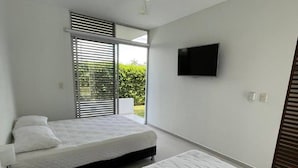 A modern bedroom with two beds, a ceiling fan, a TV, and a sliding glass door to the outside. - In Espinal Casaquinta (Espinal)