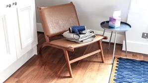 Une chaise avec une serviette et une tasse bleue, une petite table avec un boîte de mouchoirs, et un tapis bleu sur un plancher en bois.