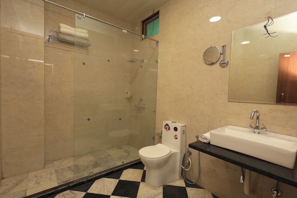 A modern bathroom with a glass-enclosed shower, a toilet, and a sink with a mirror above it.