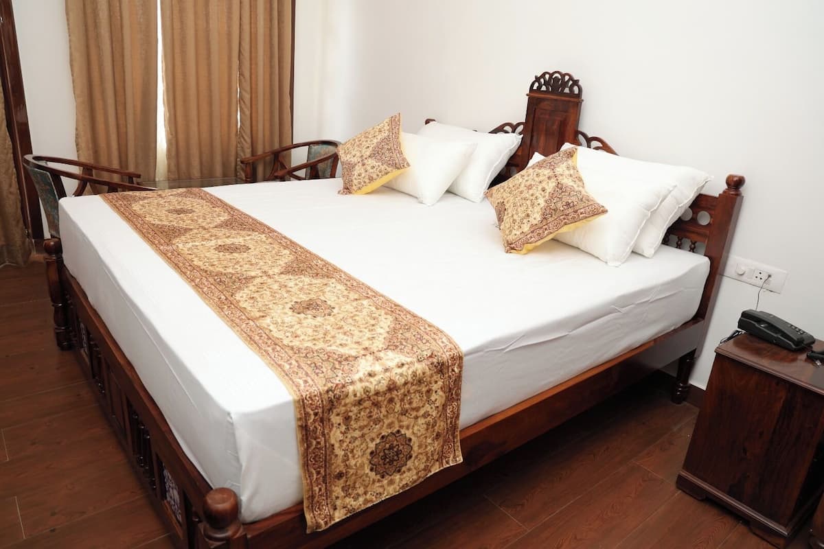 A bed with a wooden frame, white linens, and patterned pillows.