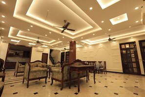 A spacious living area with a high ceiling, recessed lighting, and a central column. - MASA HAVELI (Agra)