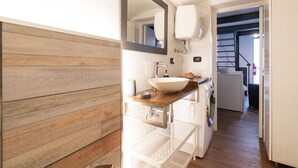 Ein modernes Badezimmer mit einem Holzkosmetikschrank, einem großen Spiegel, einem Waschbecken und einer Waschmaschine.