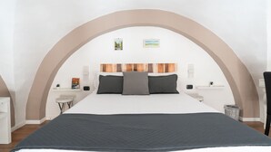 Ein modernes Schlafzimmer mit einem großen Bett, einem Holzkopfende und einem gewölbten Bogen darüber.