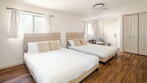 Une chambre d’hôtel avec deux lits, un plancher en bois, un bureau et une armoire.