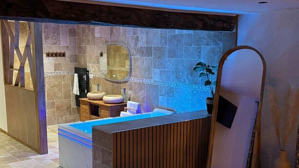 Een moderne badkamer met een vrijstaand bad, een houten wastafelmeubel en een grote spiegel.