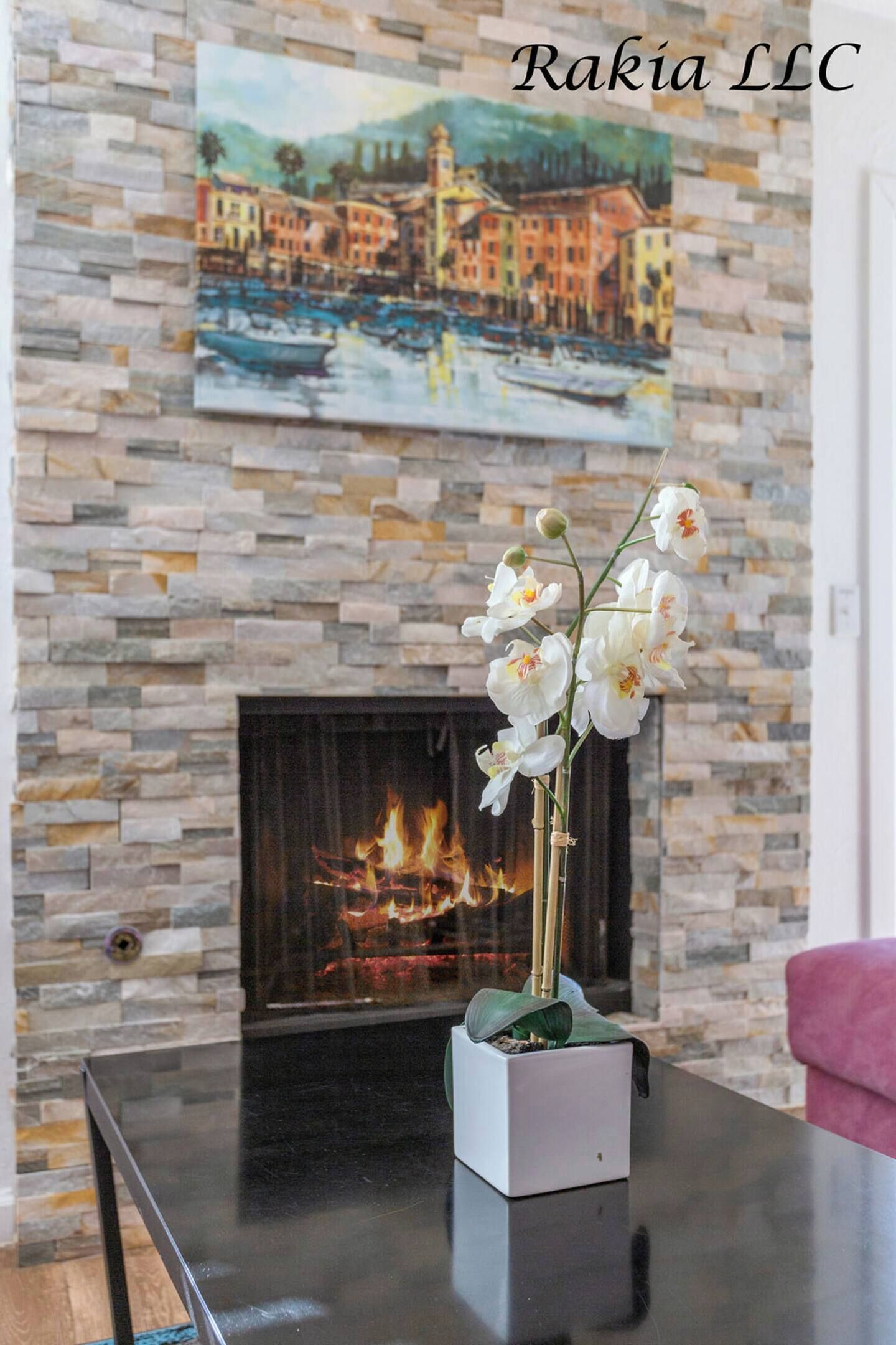 A fireplace with a stone wall and a painting above it.