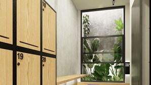 A room with wooden lockers numbered 10, 19, and 20, a window with a view of plants, and a bench with blue cushions. - Volbs (Tabanan)