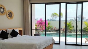 Une chambre avec un grand lit, une vue sur une piscine et un balcon agrémenté de plantes.