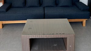 Un canapé bleu foncé avec des coussins, une table basse en osier et un logo de « Paddy’s House » fixé au mur.