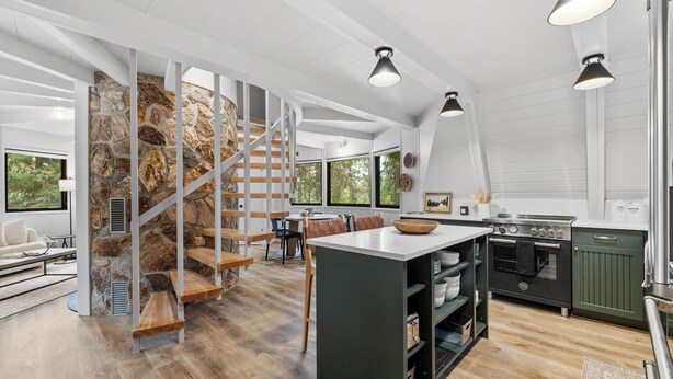 A modern kitchen with a central island, built-in appliances, and a stone accent wall. - River Cabin A-Frame-Remodeled A-Frame on the river, walk to town, lake & dining (McCall)