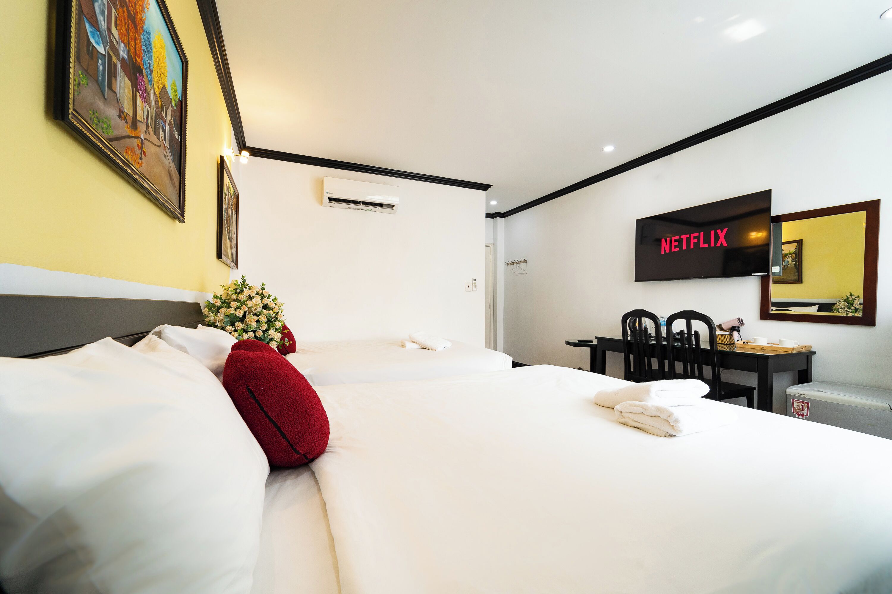 Ein Hotelzimmer mit Bett, Schreibtisch, Stuhl, Fernseher und einer Wand-Klimaanlage.