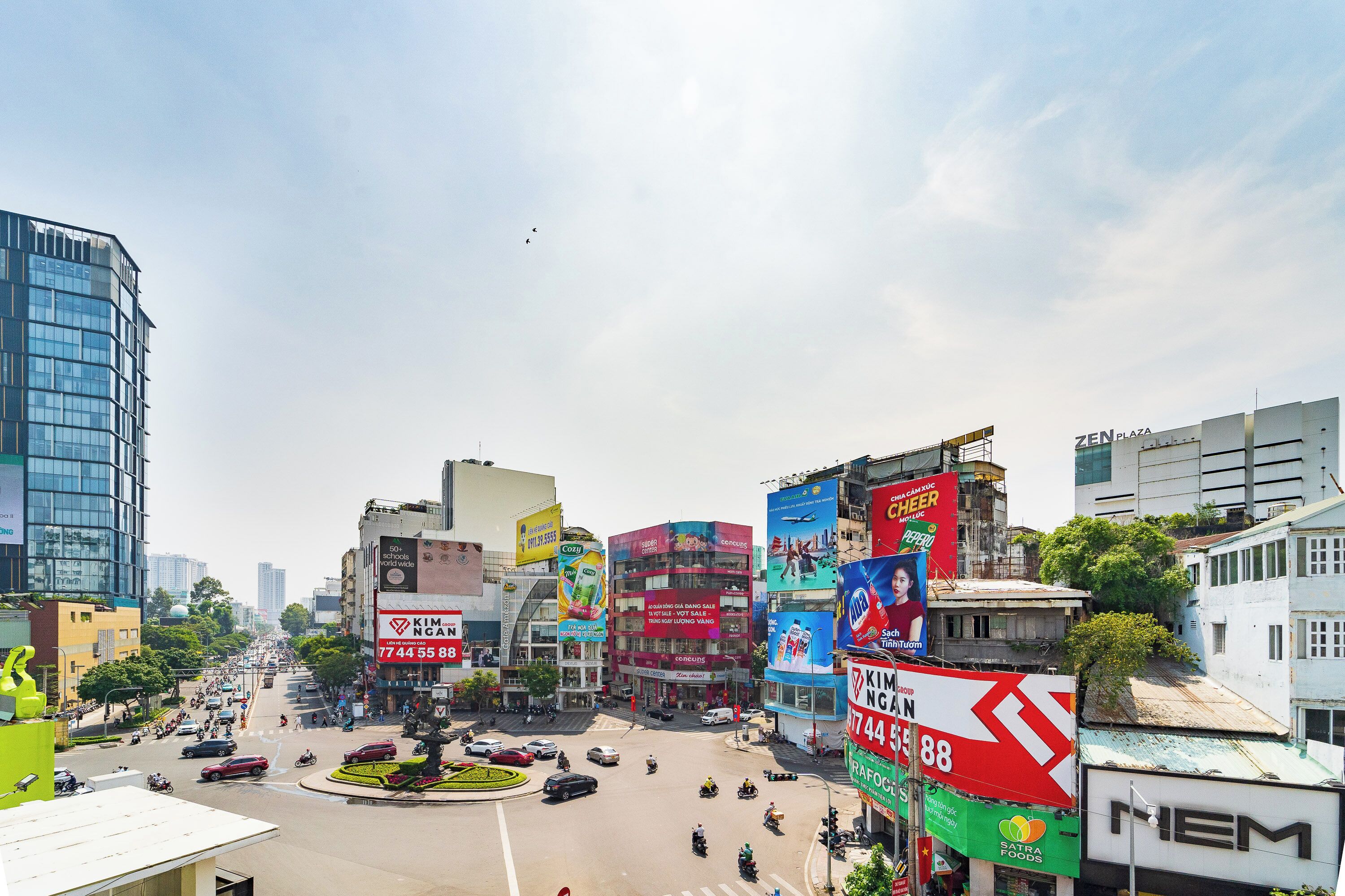 A busy urban street with multiple buildings, including a prominent red and white sign for Kim Nong Can.