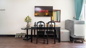 A room with a dining table, two chairs, a TV mounted on the wall, a refrigerator, and a set of shoes against the wall. - Hao Tin Hotel Ben Thanh - City Central (Ho Chi Minh City)