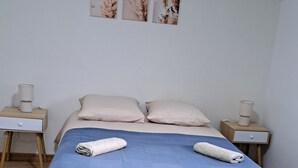 A bedroom with a bed, two nightstands, and a wall with three framed pictures.