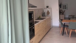 A modern kitchen with a built-in oven, a sink, and a dining area with a table and chairs.