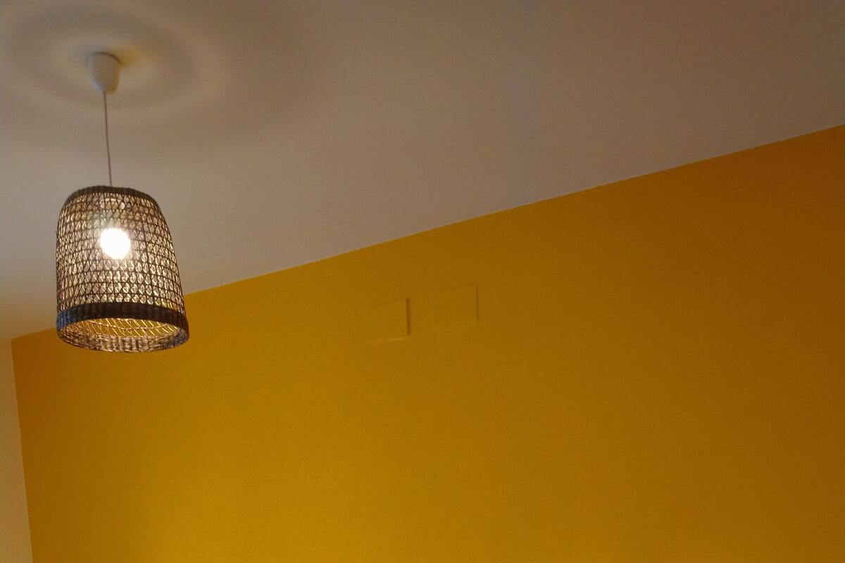 Een hotelkamer met twee bedden, elk met een andere kleur sprei, en een hanglamp.