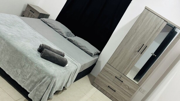 A bedroom with a bed, a nightstand, a wardrobe, and a mirror. - Ox Apartment (Suva)