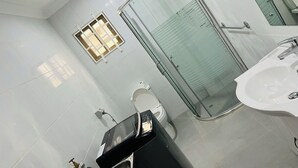A modern bathroom with a glass-enclosed shower, a toilet, and a sink. - Ox Apartment (Suva)