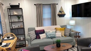 Una sala de estar acogedora con un sofá gris, una mesita de centro y una estantería.