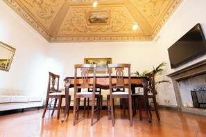 A dining area with a wooden table and chairs, a sofa, a fireplace, and a television on the wall. - Raffaello  (Perugia)