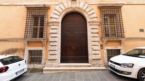 A building with a large central door, two windows with metal bars, and a white car parked in front. - Raffaello  (Perugia)