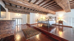 A spacious bedroom with a wooden ceiling, a large bed, a bedside table, and a rug. - Raffaello  (Perugia)