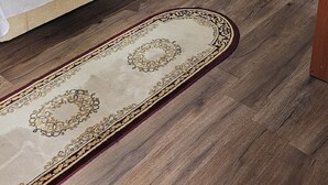 Una habitación con una cama, un sofá rojo, una mesita con una bandeja y una alfombra estampada.