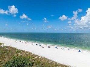 A beach with white sand and clear blue water. - Beachfront 3BR Apollo condo with heated pool and Gulf views. (Marco Island)