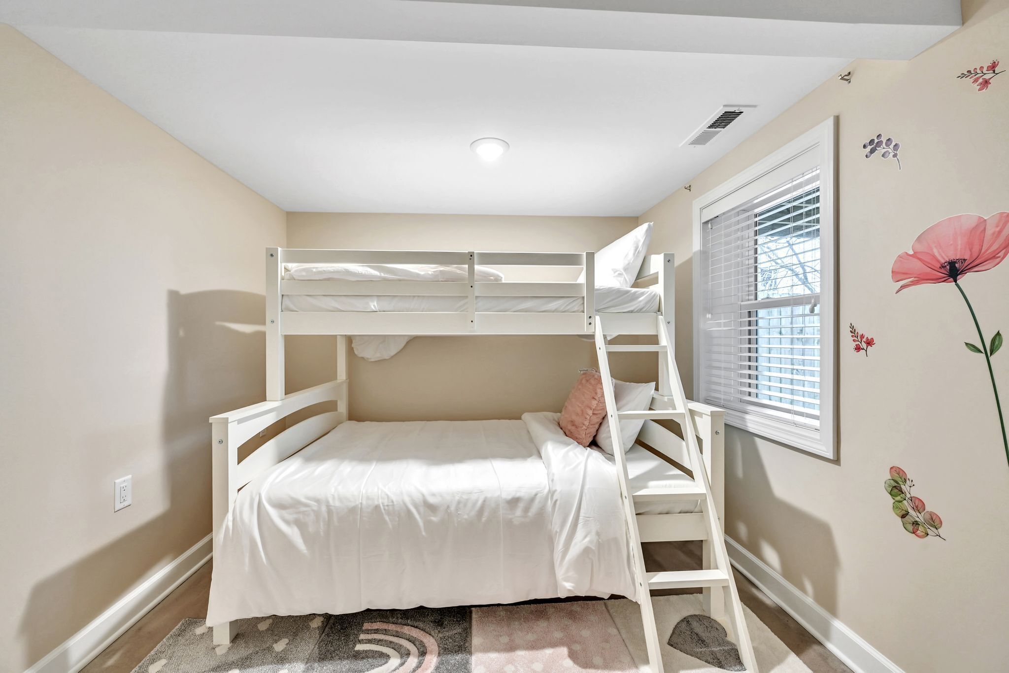 A bunk bed room with a window and a wall decoration.