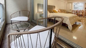 A modern bedroom with a large bed, a glass door leading to a balcony with wicker chairs and a small table. - Studio With Pool and Balcony In San Telmo (Buenos Aires)
