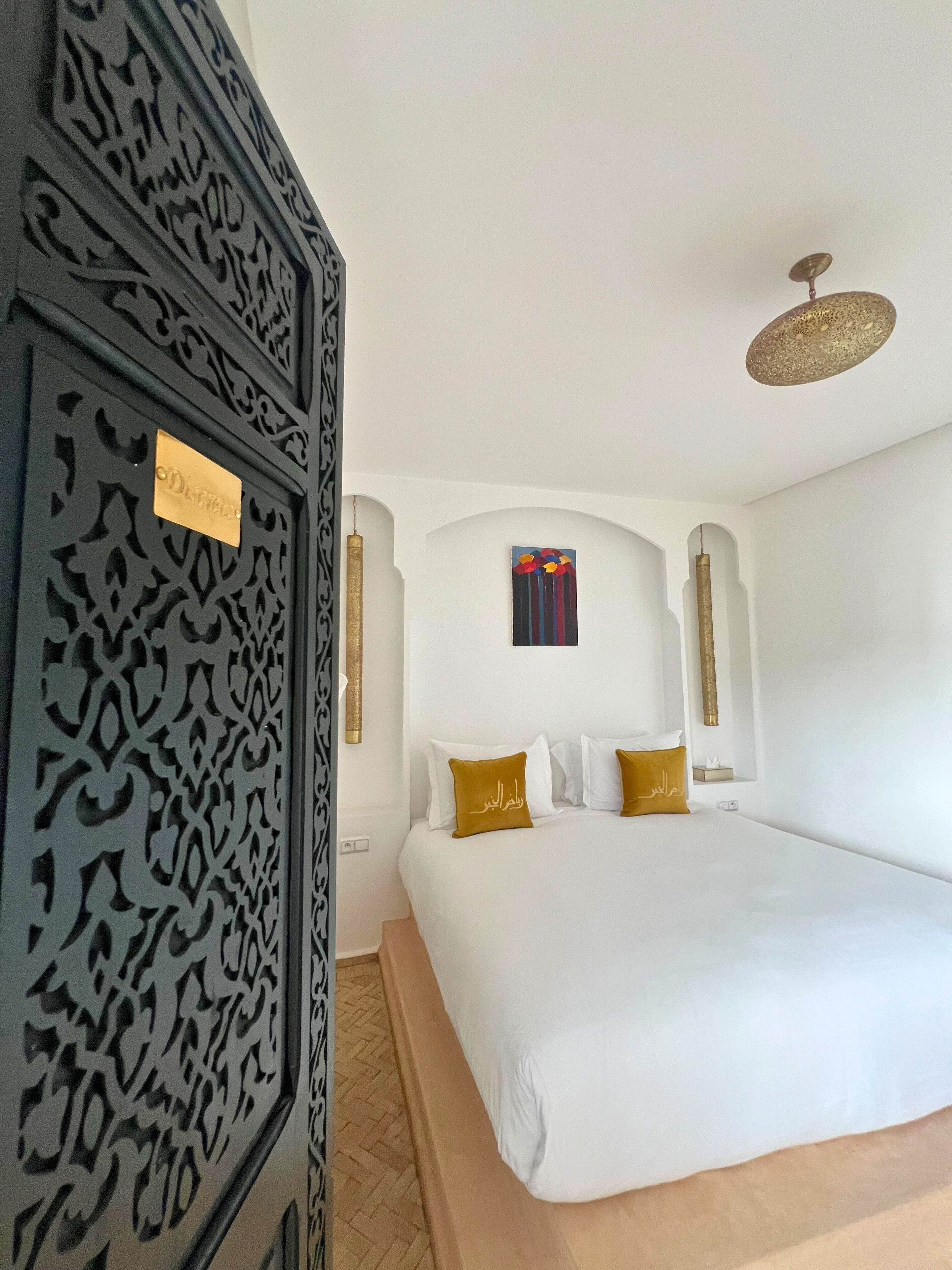 Un dormitorio con una cama grande, paredes blancas y una puerta decorativa.