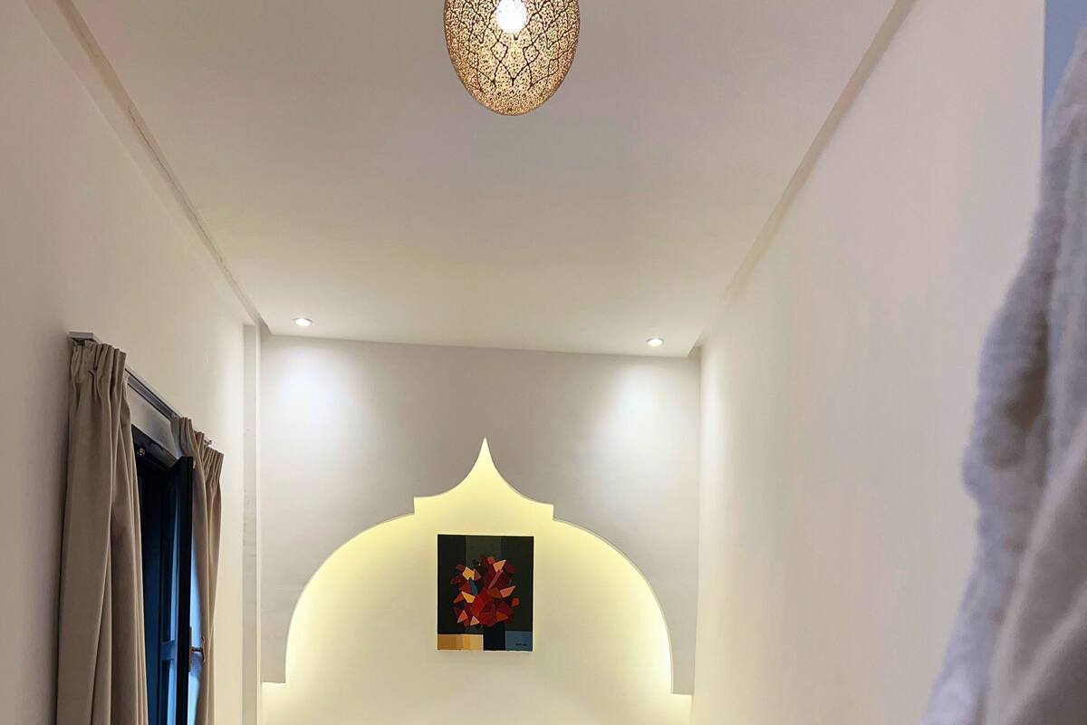 Ein Schlafzimmer mit einem Bett, Kissen, einem Teppich und einem Wandbild.