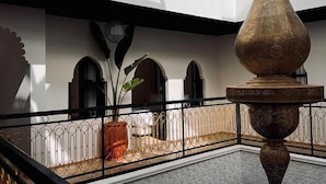 Pátio com fonte, planta em vaso e portas arqueadas.