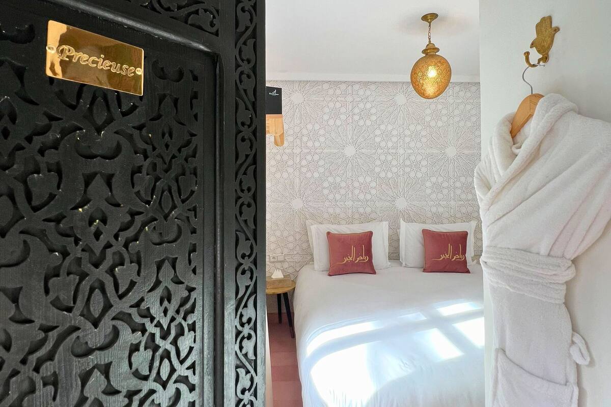 Ein Hotelzimmer mit Bett, einem an der Wand hängenden Bademantel und einer dekorativen Tür.