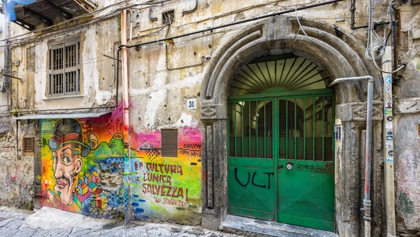 A building with a green door and a colorful mural on the wall. - Murales Street on Spanish Quarter (Naples)